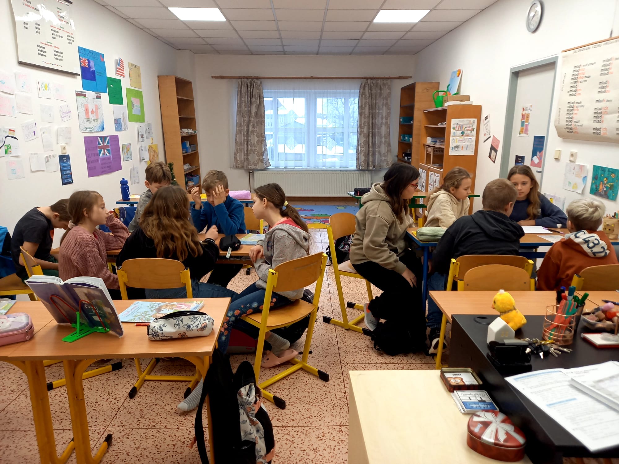 Děti ve třídě sedí v lavicích a pracují ve skupinách
