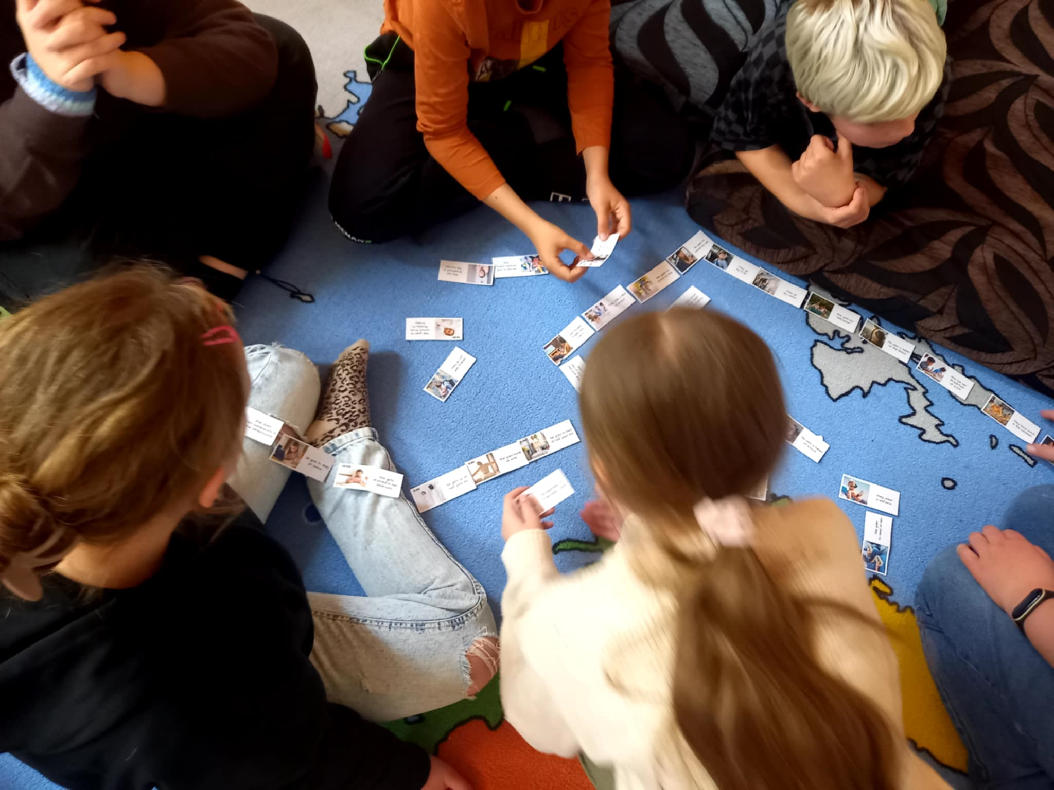 Děti na koberci hrající domino